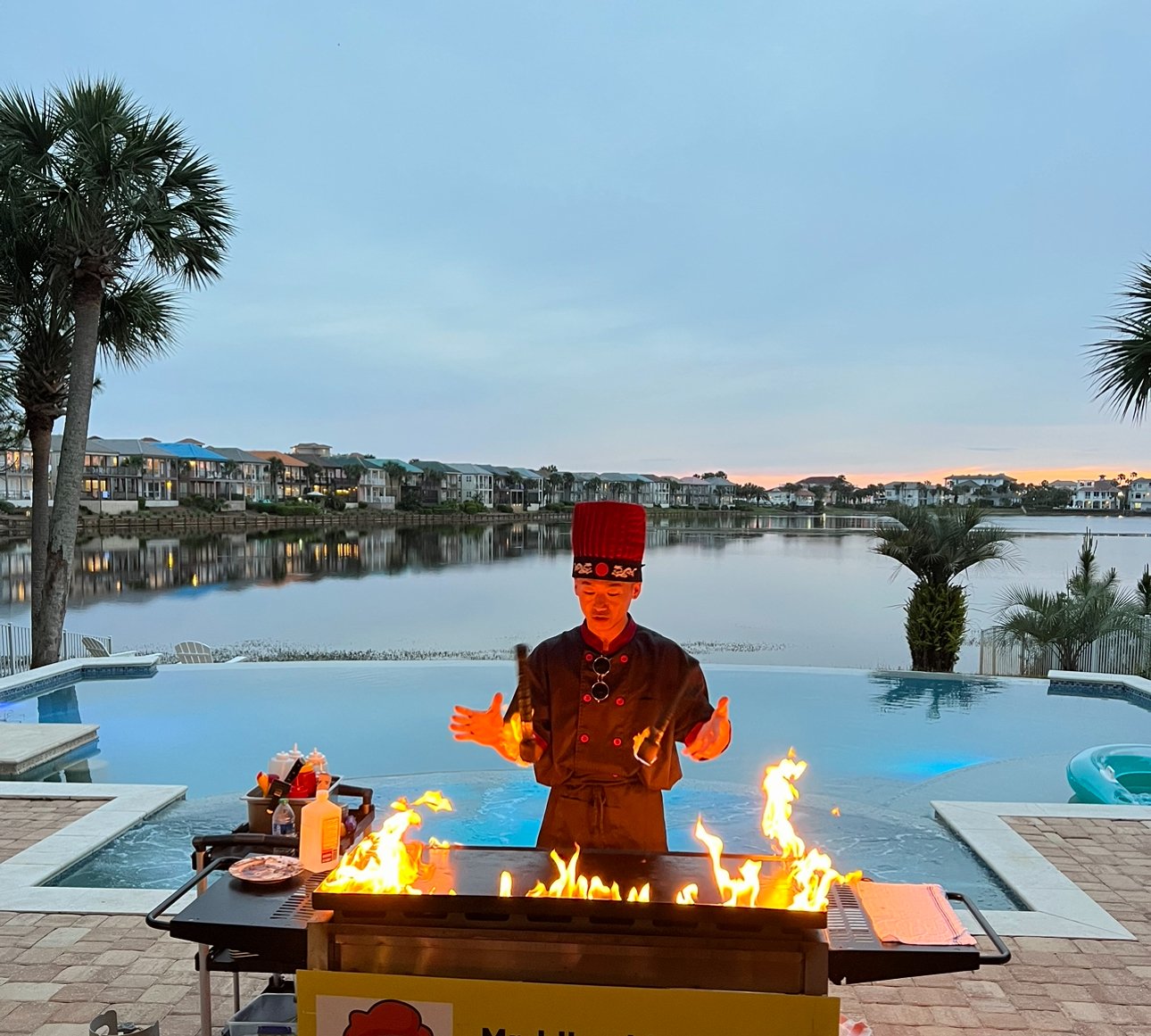 Private hibachi chef performing a flaming cooking show beside a lagoon pool in Watersound