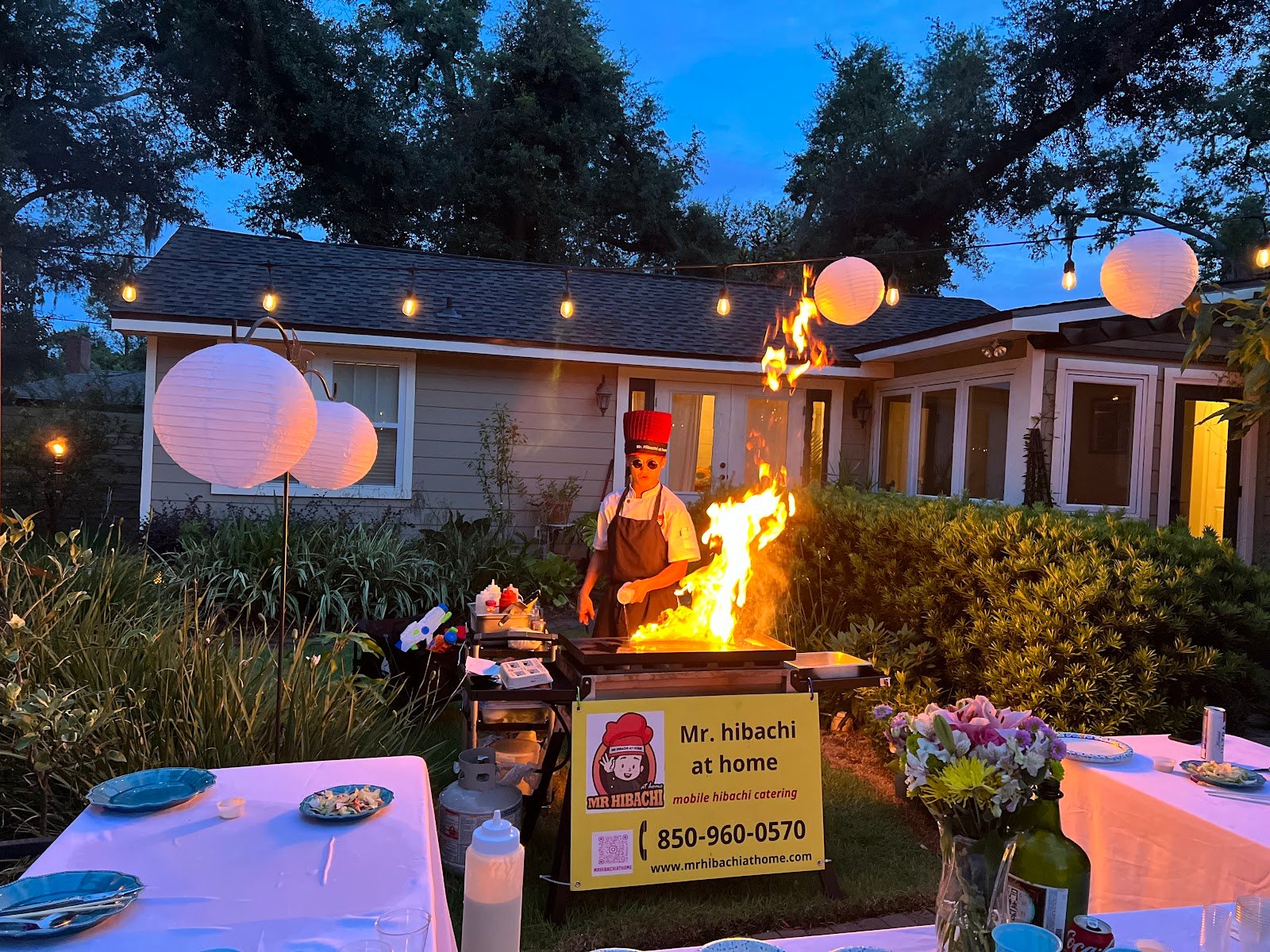 Hibachi chef preparing a festive holiday season dinner under string lights on 30A